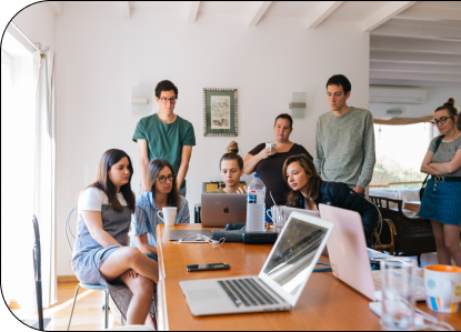 Gruppe junger Menschen bespricht sich an einem Tisch mit Laptops